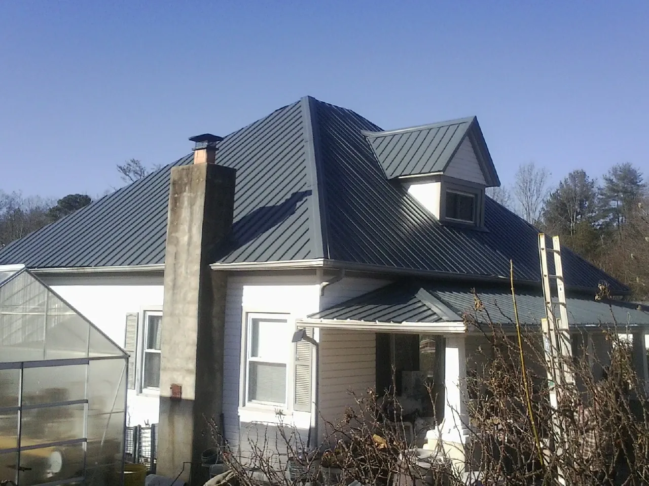 Dark blue standing seam metal roof on a white farmhouse with dormer — Slate & Tile Roof Repair by Roofing Brothers in Straughn