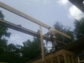 Carpenter setting a ridge beam over a new addition frame — Ice Dam Removal by Roofing Brothers in Straughn