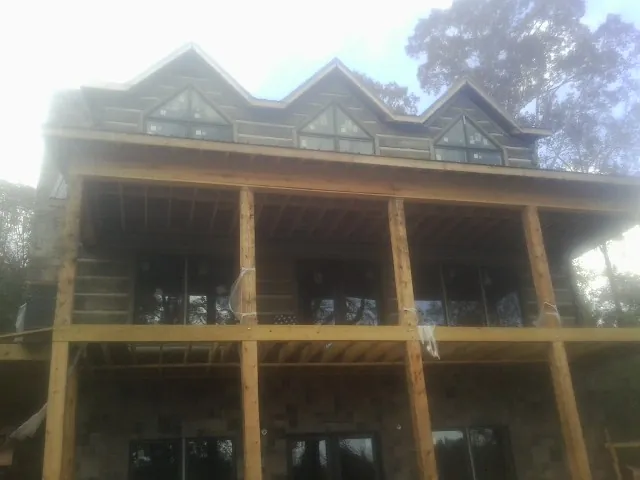 Dormers and porch framing on a large log home under construction — Roof Coating work by our crew in Straughn