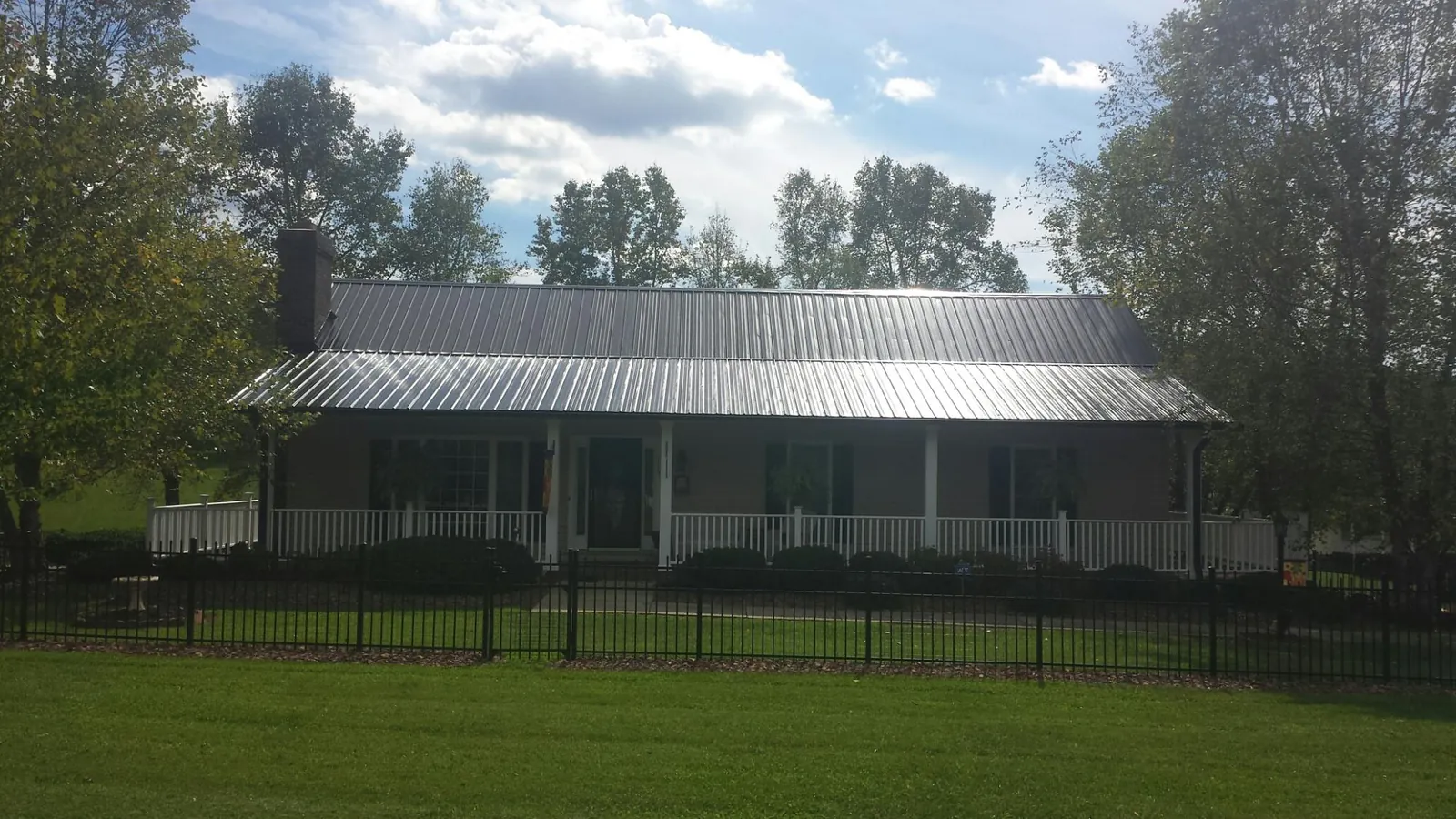 Gray metal roof on a brick ranch with a full width front porch — Gutter Guard Installation work by our crew in Straughn
