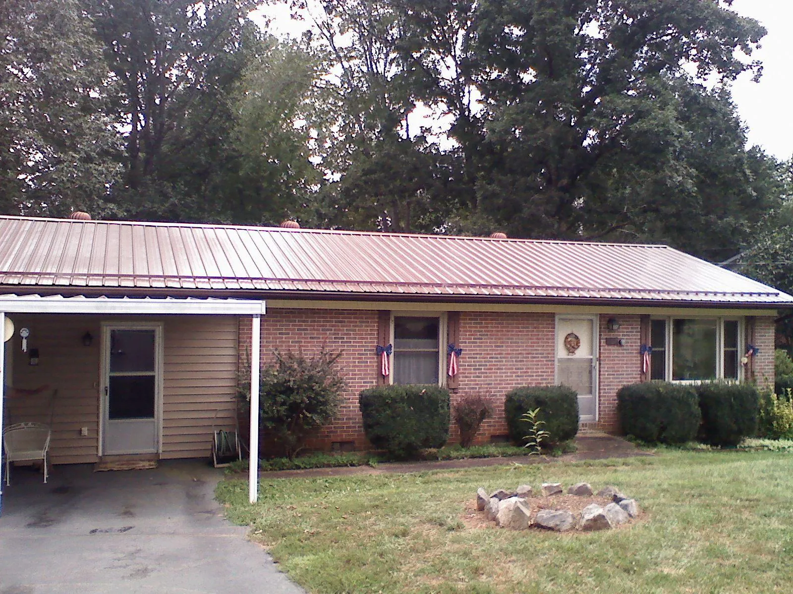 Bronze metal roof and carport on a brick ranch home — Roof Repair work by our crew in Straughn