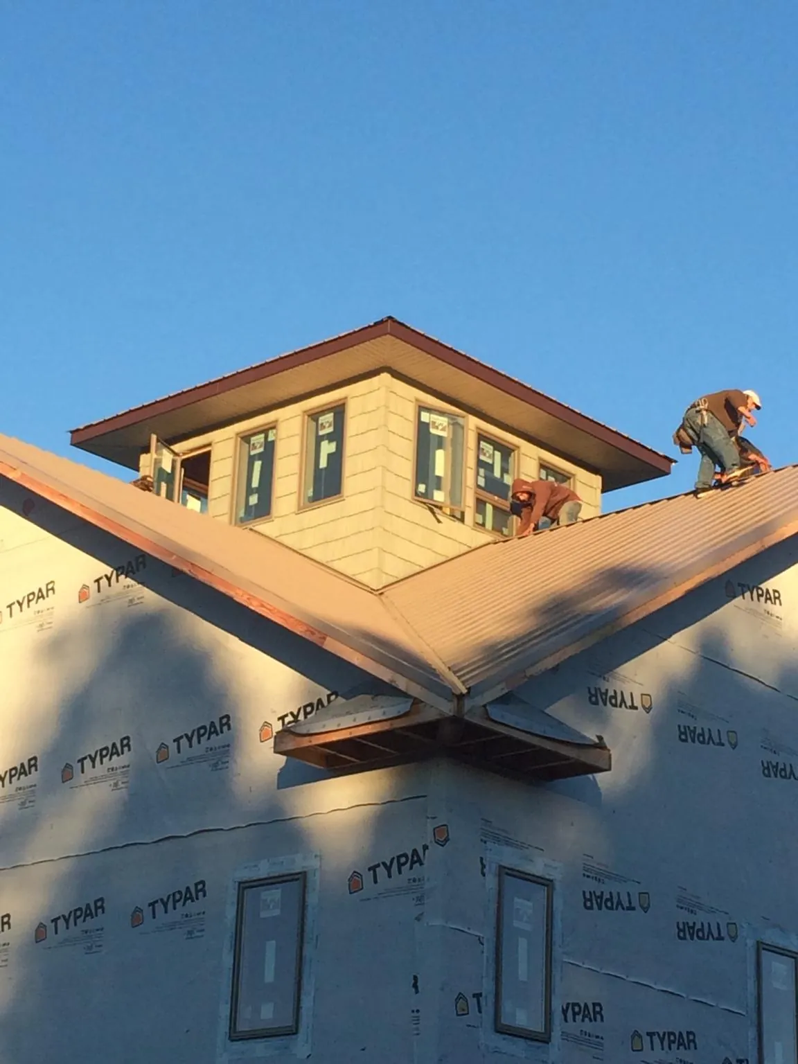 Roofers working around a rooftop cupola on a new metal roof at sunset — Roof Waterproofing in Straughn by Roofing Brothers